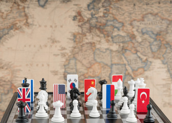 Country flag symbols on the chessboard with figures on the background of the political map of the...