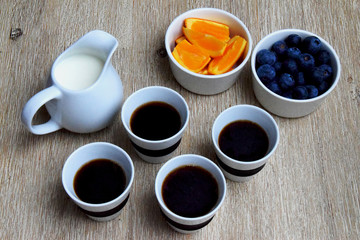 Fototapeta na wymiar Cups of coffee, milk pot and fresh blueberries and orange slices as healthy snack