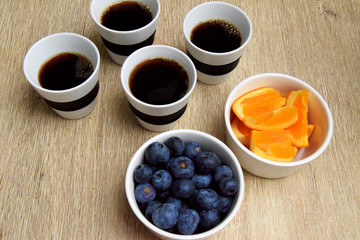 Four cups of coffee and healthy snack with orange slices and blueberries