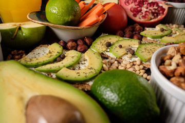 Crispbread with cheese and avocado, tomatoes, nuts, fruits, salad, spices on dark board background top view. Food and Health