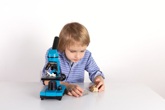 Toddler boy with a microscope a lesson of practical life on a white background, Montessori class, isolate.
