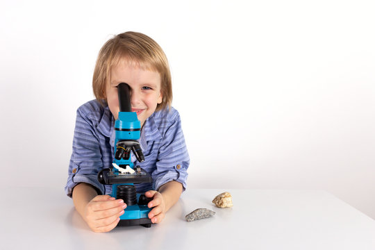 Toddler boy with a microscope a lesson of practical life on a white background, Montessori class, isolate.
