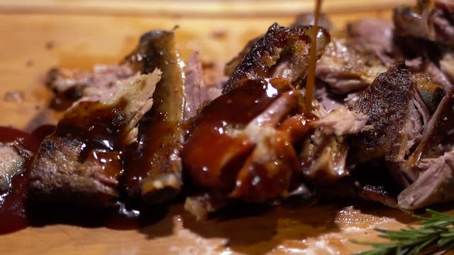 Tasty juicy ribs of beef are poured by sauce close up. Fresh meat lying on cutting board