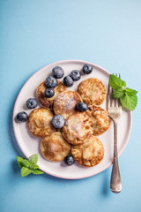 Dutch mini pancakes called poffertjes with blueberries, sprinkled with powdered sugar. Healthy food concept with copy space. Top view.