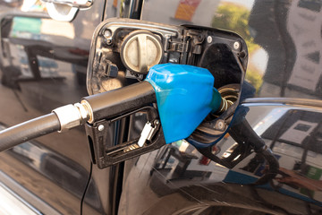 Closeup fuel nozzle to refuel oil for car in gas station.