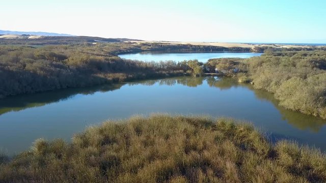 Spectacular aerial drone shot of tranquil lake in Oso Flaco, located on the Central Coast of California, Santa Barbara County. These lakes are part of the Oceano Dunes.