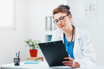 Woman Doctor Reading Lab Results in Office