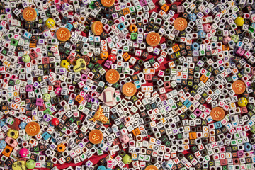 white and black cubes with holes and multi-colored letters of the English alphabet lie in a heap on a red cloth