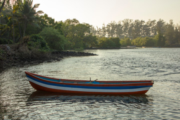 Fototapeta na wymiar white blue red empty wooden boat on the water at the shore