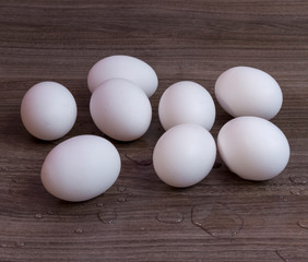 eight white eggs on a wooden table