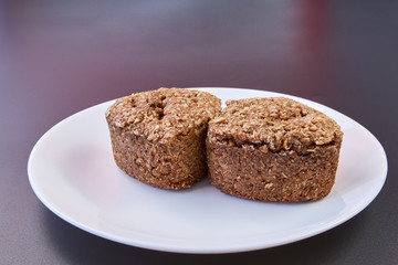 Vegan bread made at home with wheat germ and rye and buckwheat is lying on a white plate on a black background. healthy food. natural products