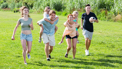 Fototapeta premium Smiling mother and father with four kids on green lawn
