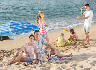 Parents and playing children on beach