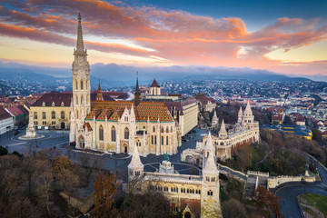 Naklejka premium Budapest, Hungary - Aerial view of Matthias Church and Fisherman's Bastion (Halaszbastya) at sunrise with beautiful golden clouds at winter time