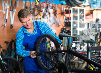 seller in uniform repairing bicycle