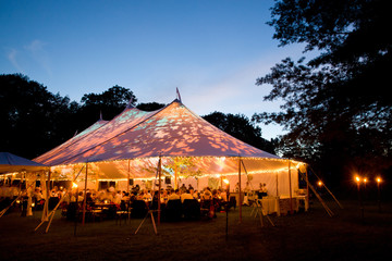 Wedding tent at night - Special event tent lit up from the inside with dark blue night time sky and...