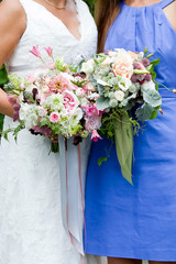 bride and bridesmaid  holding their wedding bouquet of flowers with grey and green ribbons and pink and purple flowers