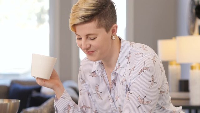 Blonde woman drinks coffee and scrolls on phone