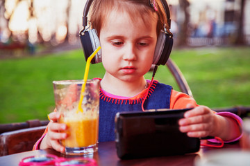 Little cute child girl using mobile phone watching online e-learning video to studying.