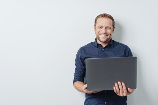 Attractive friendly man holding an open laptop