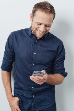 Man grinning happily reading a text message