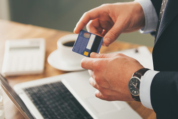 young businessman in dark office with smartphone tablet and credit card