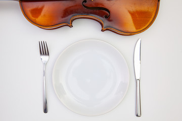 White plate and old violin on the white  wooden table.