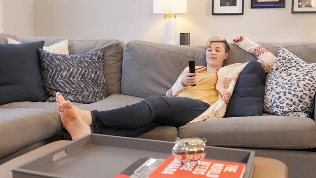 Young blonde woman with edgy pixie cut flips through channels at home