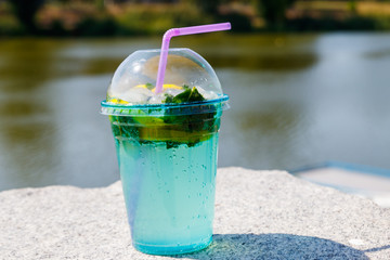 Mojito cocktail with lemon, ice and leaves of mint on a background of river