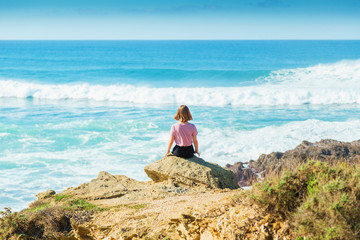 Naklejka na ściany i meble Girl looks at sea in sunny day landscape