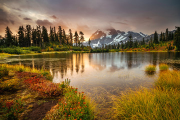 View from Picture lake of Mount Shuksan while the sunrise breaks through a incoming storm during the fall season.  