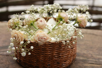 basket of pink roses wooden background