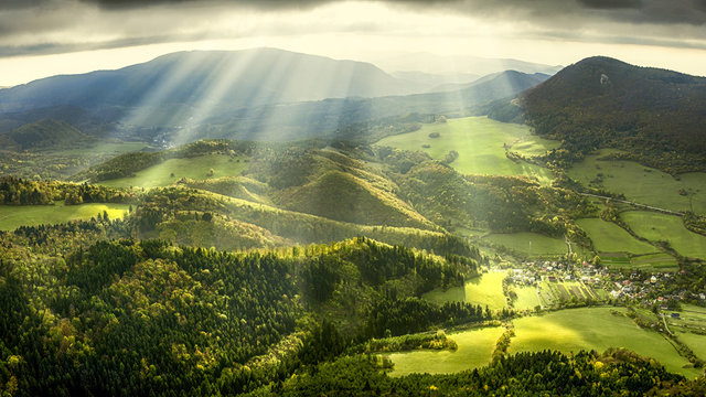 Landscape and nature in the spring. Landscape with dramatic sky and green meadows. The sun rays through the clouds.