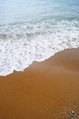 Sea foam from a little wave on the red sand of a clean deserted beach.