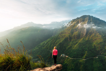 Girl meets sunrise in the mountains. Girl traveling to Sri Lanka. Mountain sports. Athlete happy finish. Mountain tourism. Walking tour. The journey to the mountains. Man on the edge of the mountain