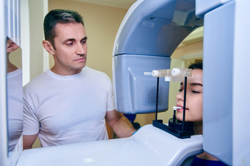 dental tomography. Girl-patient stands in a tomograph, a doctor near the control panel