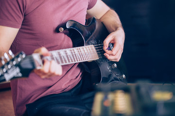 Fototapeta na wymiar Close up hand of young man playing on a professional, black electric guitar, music instrument, entertainment (color toned image)