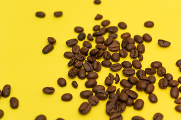 Many coffee beans scattered on a yellow background.