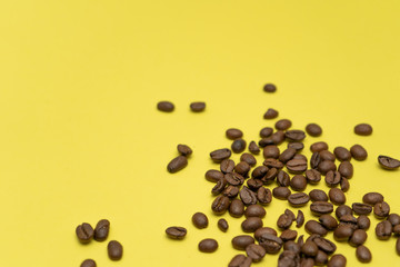 Coffee beans randomly scattered on a yellow background.