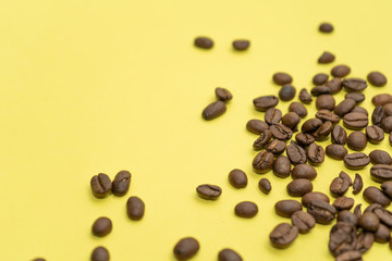 Close-up of coffee beans scattered on a yellow background.