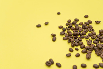 Lots of coffee beans scattered on a yellow background.