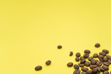 Some coffee beans are scattered on a yellow background.