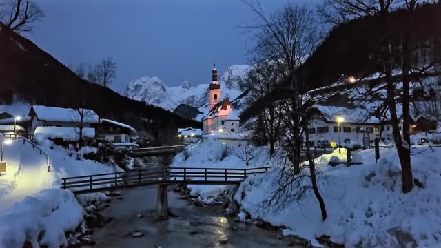 Winter morning flight over footbridge near famous Parish church St. Sebastian, in Ramsau, Berchtesgaden, Bavarian Alps Germany.