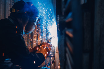 Professional welder performs welding work on metal in protective mask. Industrial concept