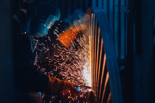 Industrial concept. Professional welder performs welding work on metal in protective mask