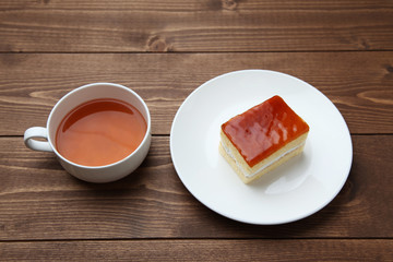 orange honey syrup cake on plate with hot tea isolated on table