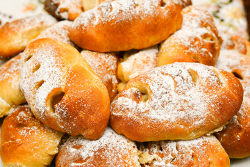 Fresh bakery, delicious, pies with powdered sugar. Cakes, small round pies containing sweet filling.