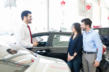 Couple Gathering Information About Automobile In Showroom