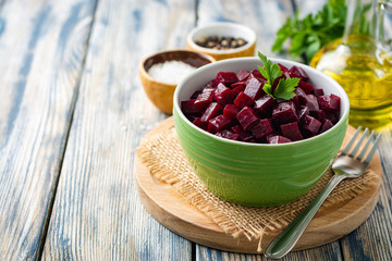 Beetroot salad with parsley in bowl on rustic wooden table. Selective focus.
