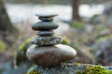 Fototapeta na wymiar Closeup of stone balance on rock covered by moss in border river